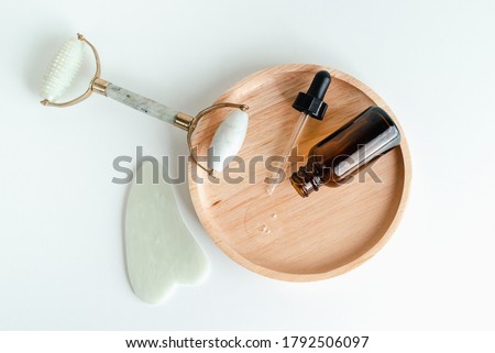 Cosmetic bottles, face serum, facial massage roller and guache scraper on background. Advertising Beauty salon, face massage. Healthy skin without wrinkles. Monochrome photo trend  Foto stock © 
