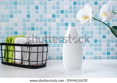 Shampoo on a white tile background. Shower gel with orchids in the bathroom. Cosmetics for skin health. Mockup for your logo. Bath mockup with copy space.  bottle of shampoo or shower gel