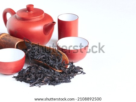 Traditional сhinese teapot made of Yixing clay, oolong 'Da hong pao' tea, wildly known under original chinese name 'Big red robe   大红袍',  wooden spoon and tea cups  on white background , copy space. 商業照片 © 