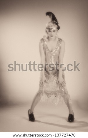 Woman dancing in a 1920\'s beaded flapper dress in sepia toned black and white.