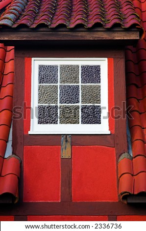 A white dormer window in a red Danish building with a tiled roof.