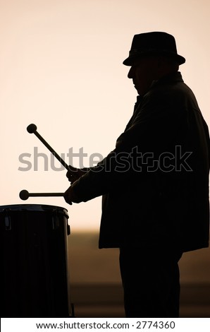 Man in a drum circle on the beach.
