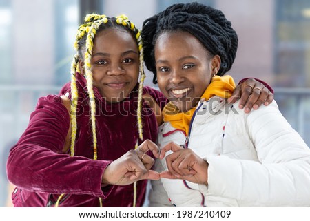 Two smiling happy black girl friends, african american homosexual women, afro lesbians couple make heart shape symbol in hands. free expression of love, lgbt rights. Lesbian couple hugging