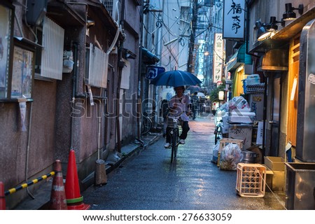 OSAKA, JAPAN - MARCH 7, 2015: Man riding bicycle in rain.