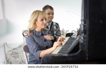 warm family portrait of mother and son near the piano
