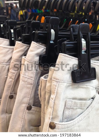Many white denim jeans on coat hanger.