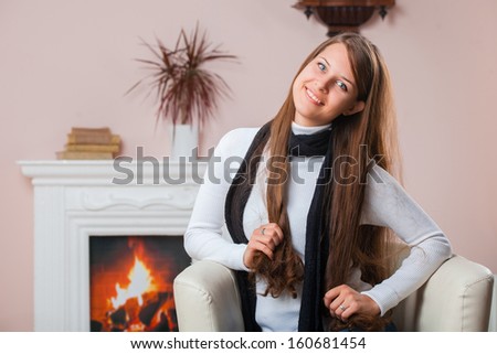 Beautiful girl in scarf sitting by the fireplace