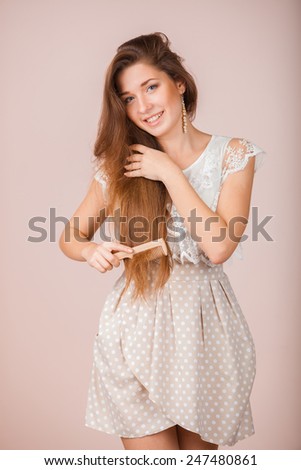 Smiling Beautiful girl combs her hair over pink background