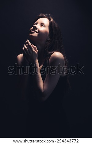 Pretty young woman in black t-shirt over dark studio background