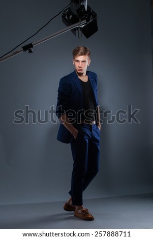 Portrait of handsome guy posing in studio on gray background