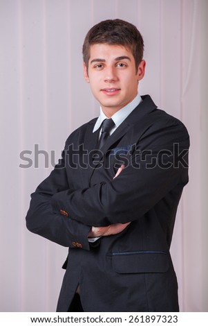 Casual Young Man in suit Standing With His Arm Crossed. Shot in office