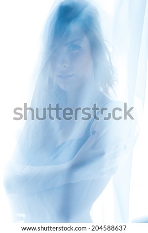 hiding behind curtain tulle seductive slim blond pretty lady having fun standing in bikini or undies happy smiling relaxing looking at camera over window light copy space background portrait closeup