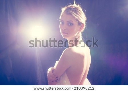 portrait of romantic attractive blond performer sexy tender girl having fun posing back side half naked standing hugging herself on black light flare copy space background