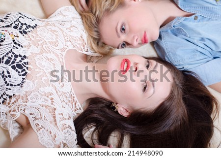 head to head: 2 sexy pretty best girl friends with red lipstick having fun relaxing in bed and one looking at camera while other looking at her