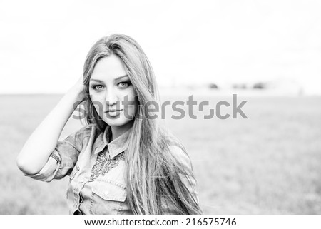 black and white closeup portrait of beautiful brunette young woman having fun relaxing happy smiling and looking at camera on summer field outdoors copy space background