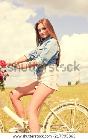 enjoying cycling series: portrait of beautiful brunette young woman having fun with bicycle on green summer outdoors copy space background