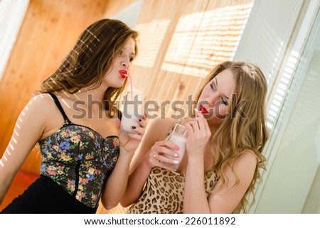 joyful time: portrait of 2 sexy romantic beautiful girlfriends in bodice having fun & good time drinking cokctails on sunny wooden wall copy space background