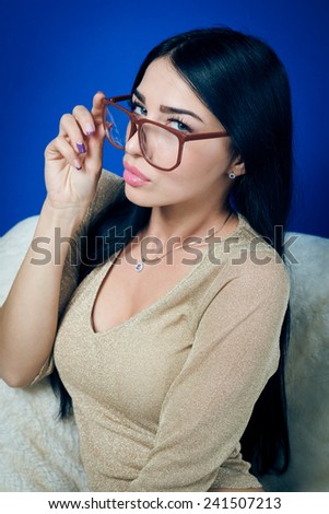 portrait of young pretty lady in glasses relaxing sitting on chair & flirty looking at camera