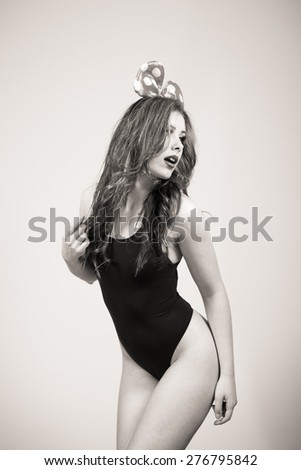 Black and white portrait of sexy beautiful young lady having fun wearing bunny ears posing on light copy space background
