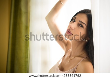 Close up portrait of beautiful young lady relaxing at the window and happy looking at camera