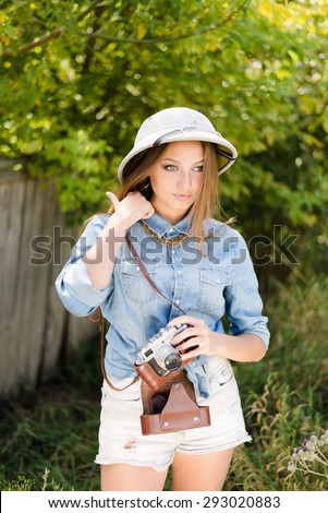 Picture of young beautiful woman in pith hat taking pictures on retro camera on green trees summer copy space background