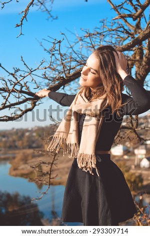 Portrait of young pretty woman standing at tree by river and having fun relaxing on sunny outdoors copy space background