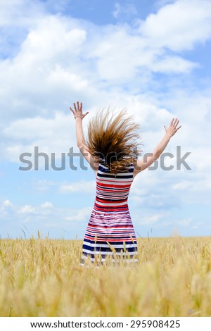 Picture of beautiful female having fun standing in the field and holding hands up on blue sky copy space background