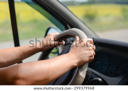 Man\'s hands gripping wheel of car