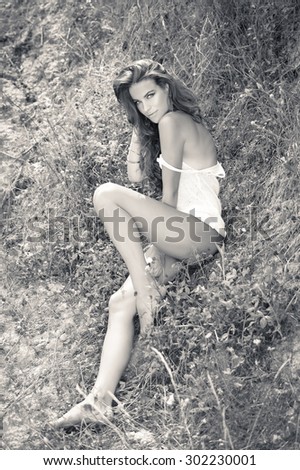 Picture of glamour sexi young pretty lady sitting on the ground outdoors, black and white portrait