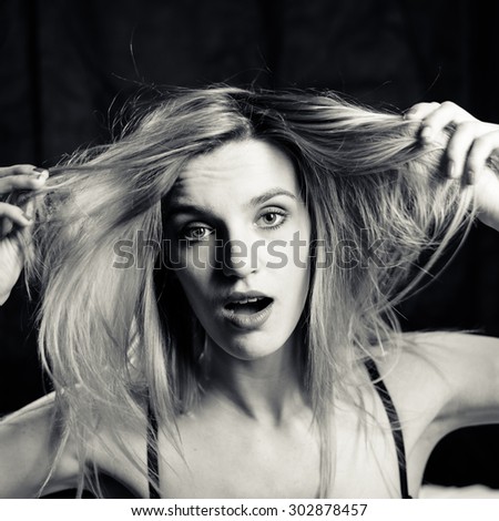 Beautiful female holding hair with hands up. Black and white photography