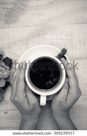 Black and white picture of hands embracing cup of coffee