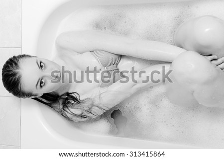 Portrait of beautiful sexy lady in bikini using luxury spa bath for relaxation. Black and white image