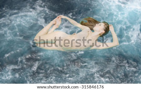 Picture of beautiful young lady floating in light beige swimsuit. Sexi girl bending on blue toned stormy underwater background. Filtered copy space image