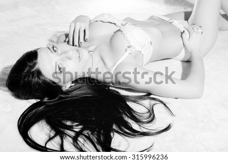 Black and white photography portrait of amazing sexy beautiful young lady in great shape with long luxury hair relaxing on light copy space background.