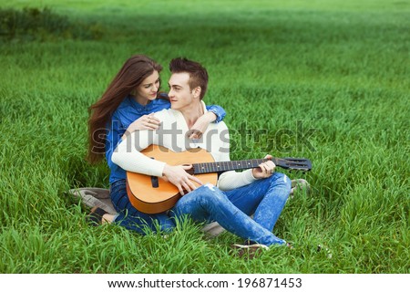 young guy playing guitar for his girlfriend