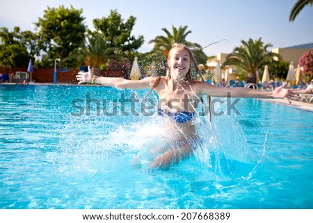 Young beautiful slim girl jumping into the pool