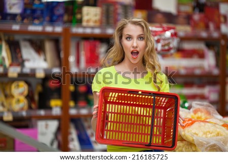 Beautiful girl in the store with a basket of products in the hands of