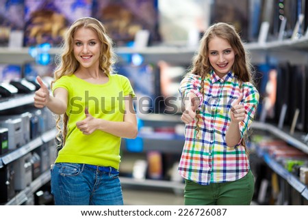 Two beautiful girls choose TVs in shop