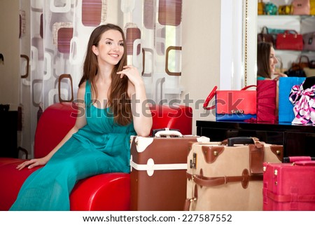 Beautiful young girl in a green dress sitting with suitcases and bags in store bags. Shopping