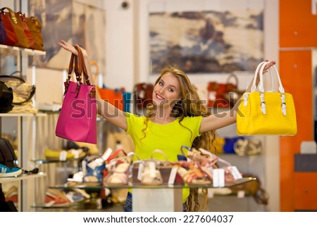 Beautiful young blonde in shop chooses bags shoes and bags. Shopping