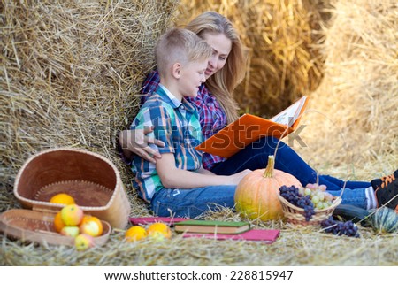Mom and son read read books on hay autumn day