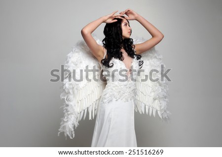 Sweet girl with a beautiful face in the form of an angel posing on gray background.Isolated studio portrait