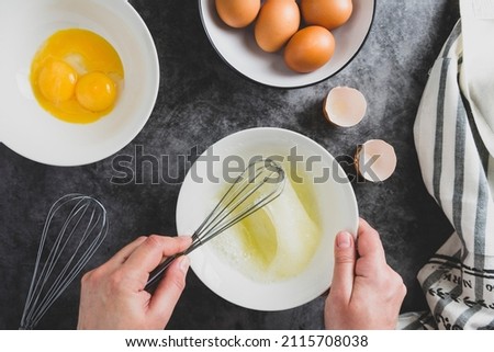 Cooking omlette. Woman's hands cookingomlette, breaking an fresh egg. Dark background. Food flat lay. Stock fotó © 