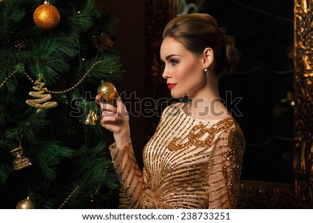 fashion woman hanged a  on the Christmas tree, stylized as gold