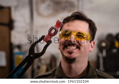 Similar – Image, Stock Photo Focused young blacksmith heating and striking metal on anvil in workshop