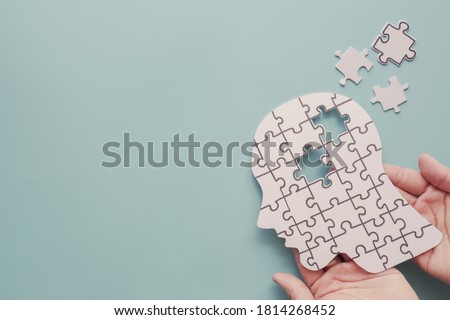 Hands holding brain with puzzle paper cutout, autism, memory loss, dementia, epilepsy and alzheimer awareness, world mental health day, world Parkinson day concept