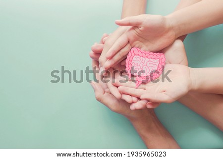 adult and child hands holding intestine shape, healthy bowel degestion, leaky gut, probiotics and prebotics for gut health, colon, gastric, stomach cancer concept