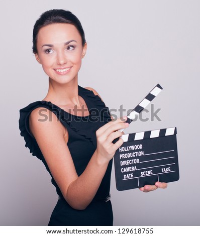 An attractive young woman holds an open film slate