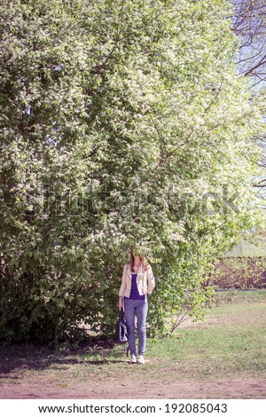 Woman stands under the big bird-cherry tree in blossom