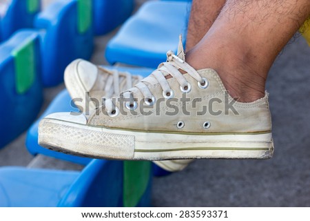 Feet in canvas sneaker on Stadium Seat